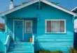 Rumah kayu warna biru terang terlihat menonjol, menjadi inspirasi pilihan warna cat rumah yang berani
