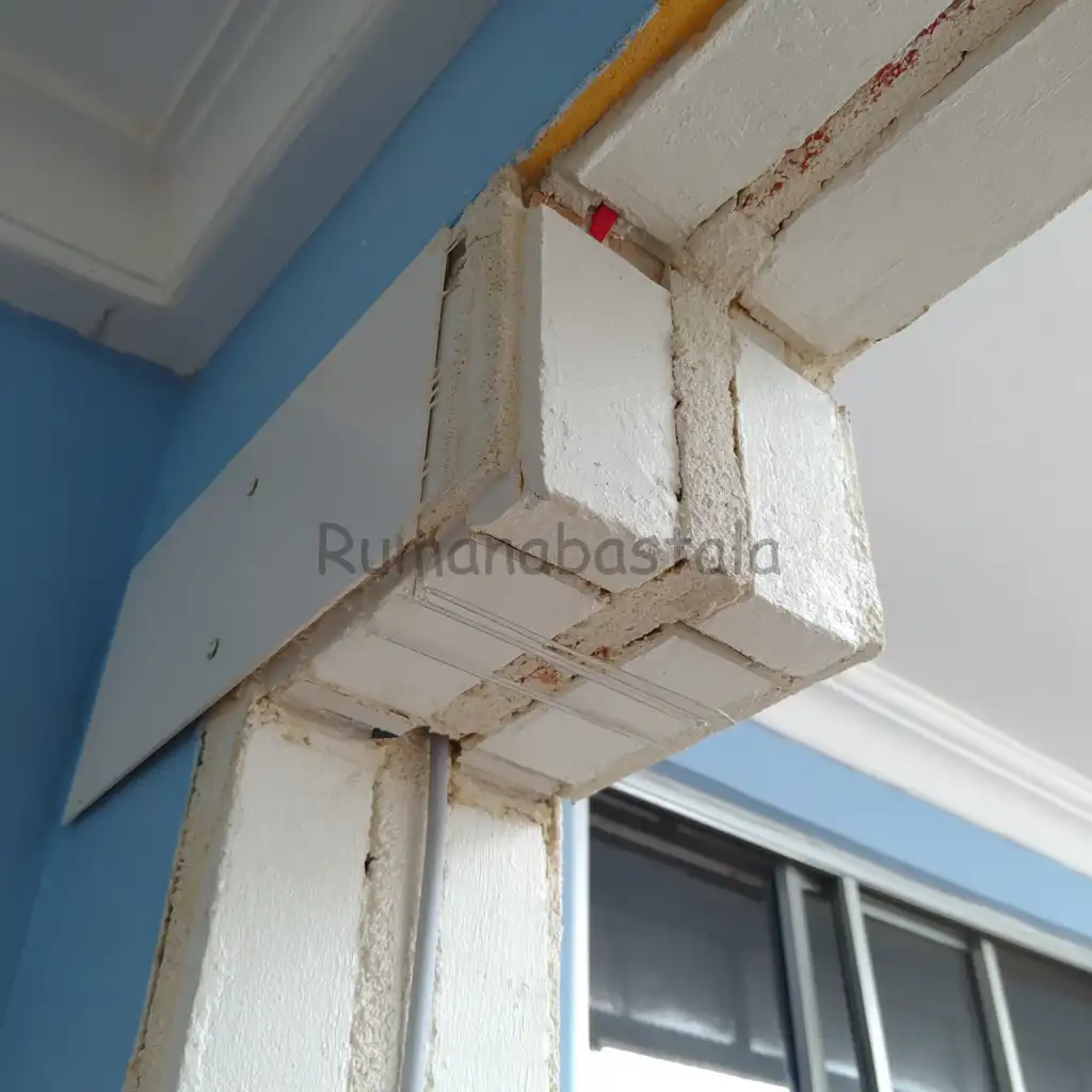 Trunking putih tersembunyi di sudut dinding rumah, efektif menyembunyikan kabel dan colokan supaya rumah tetap rapi